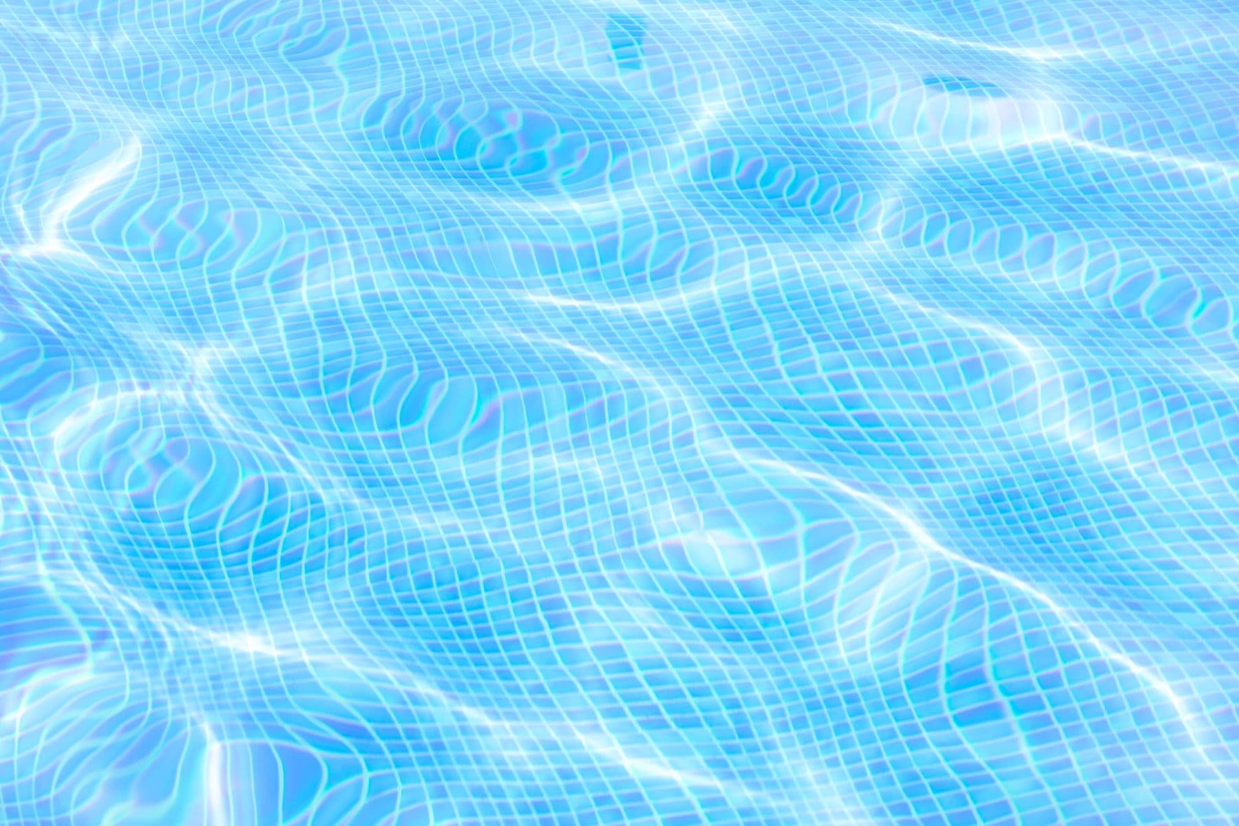 Sunlight rippling across the blue water surface of a swimming pool